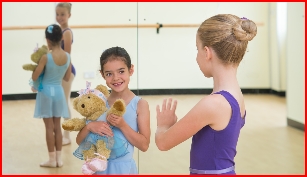 Junior ballet grade dancer waves to pre-school dancer